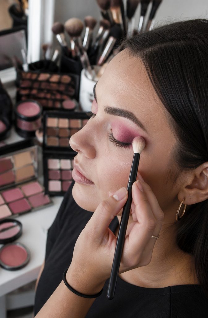 Pink Smokey Eye Makeup Tutorial: 14 Steps for a Soft, Bold Look 17 Close-up of a hand blending pink eyeshadow with a fluffy brush.